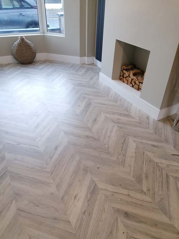 Laminate wooden effect flooring in living room with white skirting